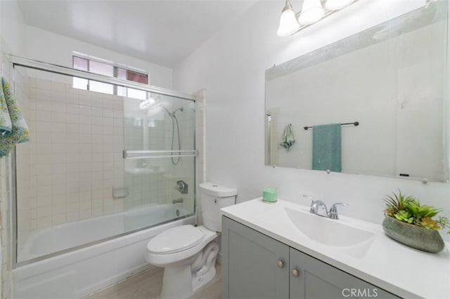 full bathroom featuring toilet, bath / shower combo with glass door, and vanity