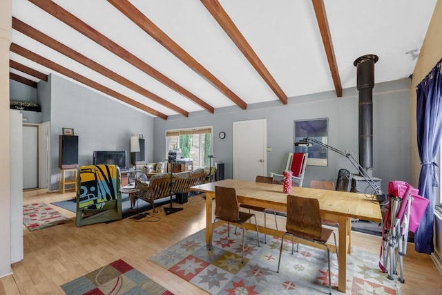 dining space with light wood-type flooring, lofted ceiling, and a wood stove