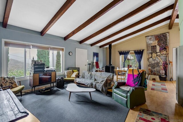 living room featuring vaulted ceiling, a wood stove, and wood-type flooring