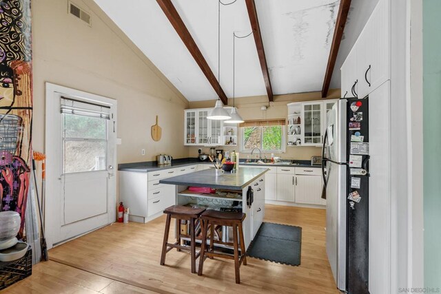 kitchen with white cabinetry, light hardwood / wood-style floors, stainless steel fridge, a kitchen island, and pendant lighting