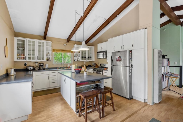 kitchen featuring white cabinets, decorative light fixtures, a kitchen bar, stainless steel appliances, and high vaulted ceiling