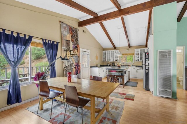 dining room featuring light hardwood / wood-style floors, sink, high vaulted ceiling, and beamed ceiling