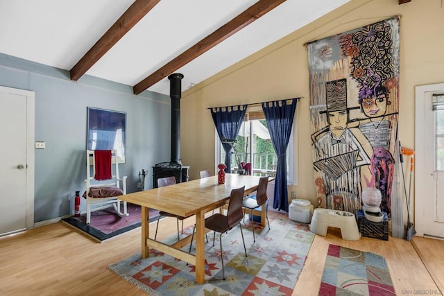 dining area featuring high vaulted ceiling, a wood stove, wood-type flooring, and beam ceiling