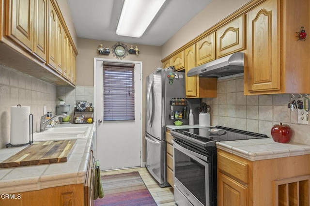 kitchen with appliances with stainless steel finishes, tile countertops, decorative backsplash, and sink