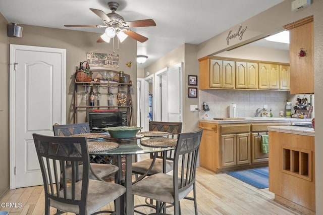 kitchen with ceiling fan, backsplash, light brown cabinetry, and light wood-type flooring