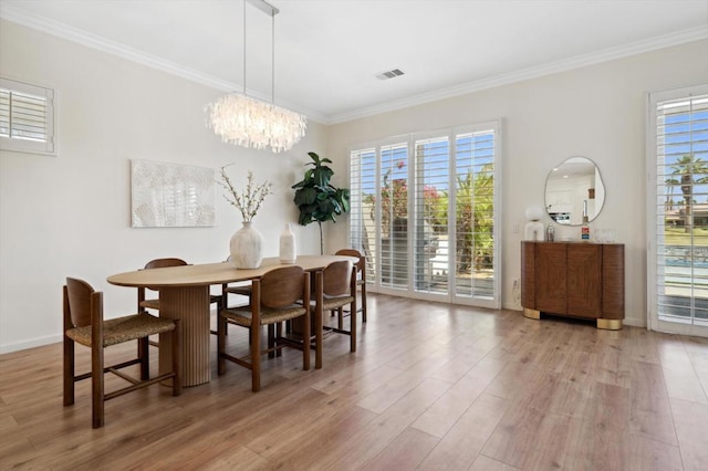 dining room with light wood-type flooring, ornamental molding, and a notable chandelier