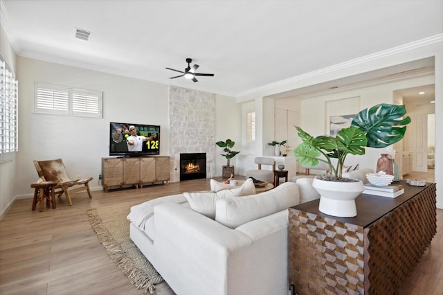 living room with ceiling fan, hardwood / wood-style floors, ornamental molding, and a fireplace