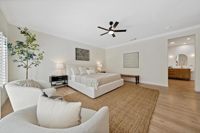 bedroom featuring ceiling fan, ornamental molding, light hardwood / wood-style flooring, and ensuite bath