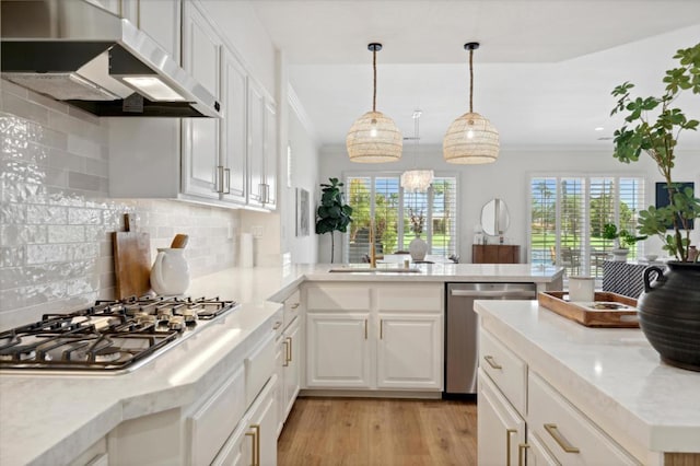 kitchen with decorative light fixtures, kitchen peninsula, sink, appliances with stainless steel finishes, and white cabinets