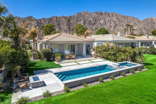 back of property featuring a swimming pool with hot tub, a mountain view, a lawn, and a patio