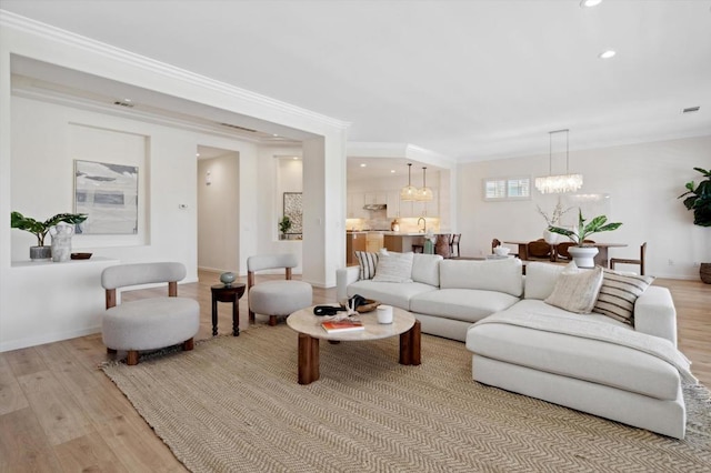 living room featuring light hardwood / wood-style flooring, ornamental molding, and a chandelier