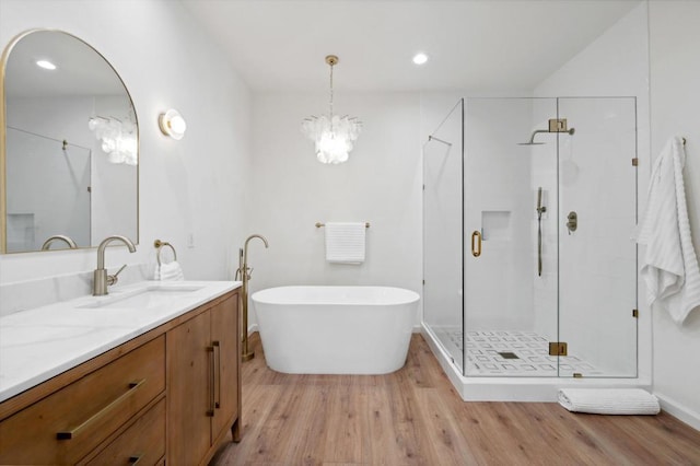 bathroom featuring vanity, plus walk in shower, a chandelier, and hardwood / wood-style floors