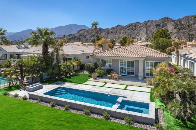 rear view of house featuring a pool with hot tub, a patio area, a mountain view, and a lawn