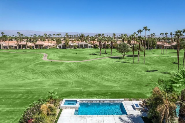 view of home's community with a lawn, a hot tub, and a mountain view