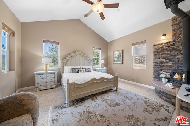 carpeted bedroom featuring ceiling fan, lofted ceiling, and a wood stove