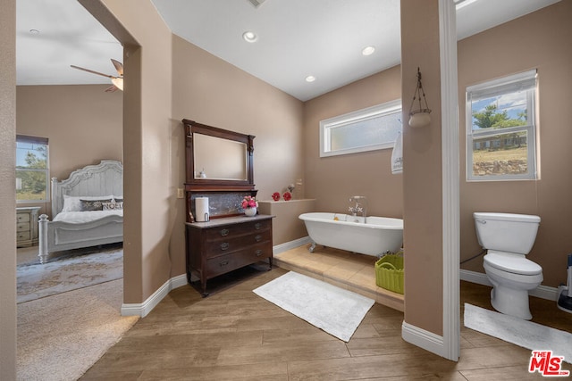 bathroom with ceiling fan, a bathing tub, toilet, and hardwood / wood-style flooring