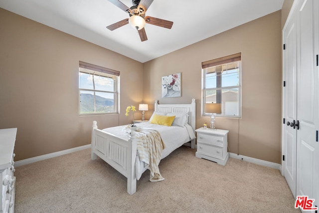 bedroom featuring ceiling fan, light carpet, and multiple windows