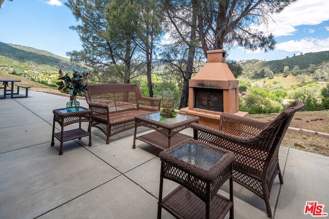 view of patio with a mountain view and an outdoor living space with a fireplace