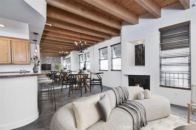 living room featuring beam ceiling, a notable chandelier, concrete floors, and wooden ceiling