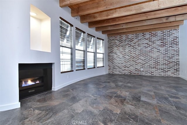 unfurnished living room featuring brick wall and beamed ceiling