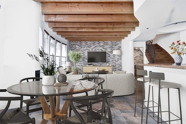 dining space featuring brick wall and beam ceiling