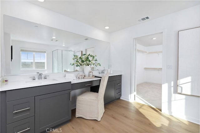 bathroom with hardwood / wood-style flooring, a shower with door, and vanity