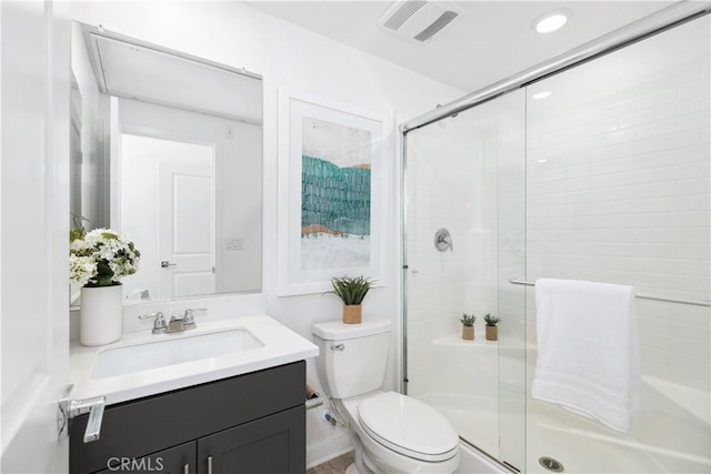 bathroom featuring toilet, vanity, and a shower with door