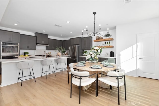 dining space with sink, an inviting chandelier, and light hardwood / wood-style floors