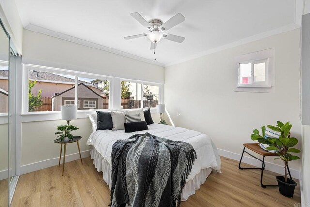 bedroom featuring ceiling fan, ornamental molding, and light hardwood / wood-style flooring