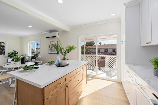 kitchen featuring white cabinetry, light stone countertops, light hardwood / wood-style floors, and a wall mounted AC