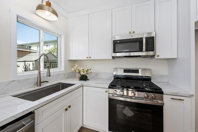 kitchen featuring white cabinetry, appliances with stainless steel finishes, sink, and light stone counters