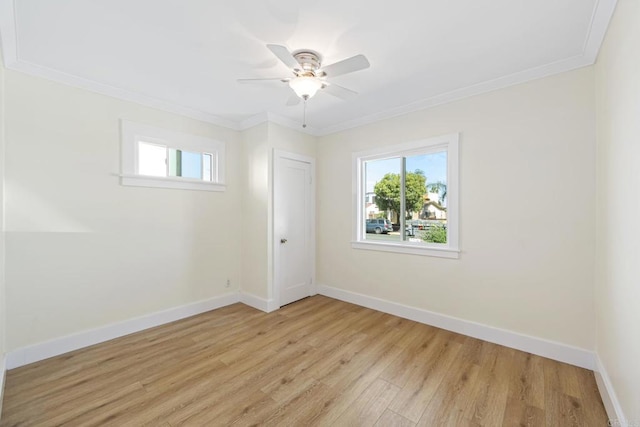 empty room with crown molding, a healthy amount of sunlight, and light hardwood / wood-style flooring