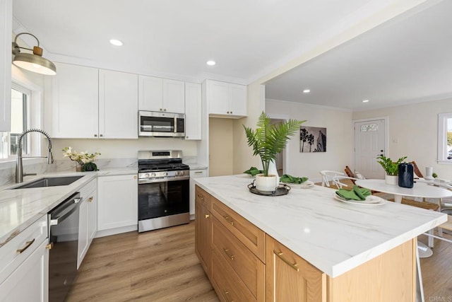 kitchen with sink, a kitchen island, white cabinets, and appliances with stainless steel finishes