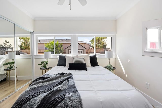 bedroom featuring multiple windows, ornamental molding, hardwood / wood-style floors, and ceiling fan