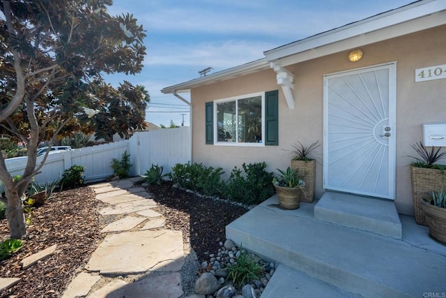 entrance to property with fence and stucco siding