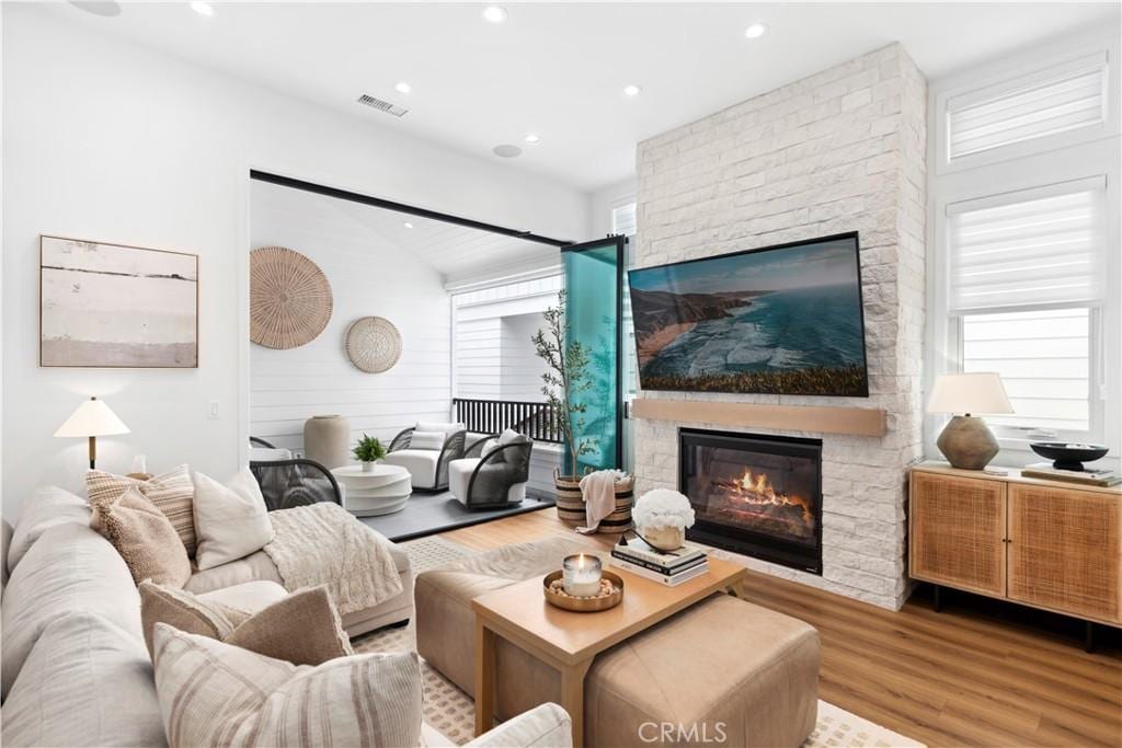 living room with plenty of natural light, a stone fireplace, and hardwood / wood-style floors