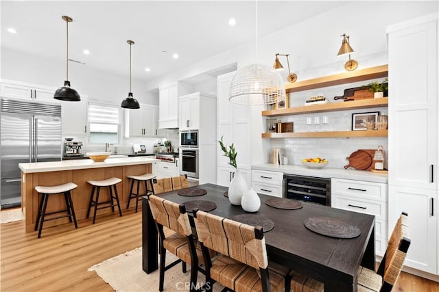 dining space featuring sink, beverage cooler, and light hardwood / wood-style floors