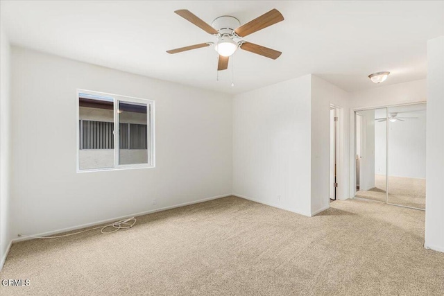 empty room featuring ceiling fan and light colored carpet