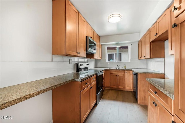 kitchen featuring tasteful backsplash, stone counters, light hardwood / wood-style floors, sink, and appliances with stainless steel finishes