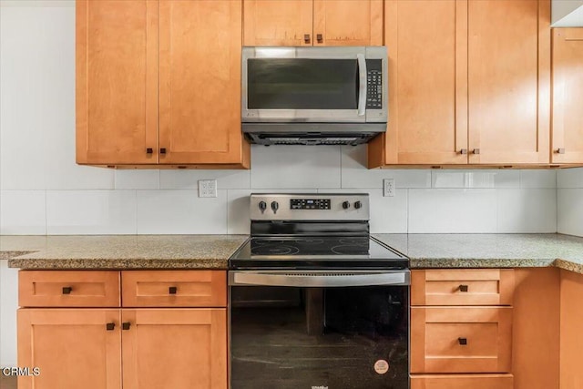 kitchen featuring light stone counters, appliances with stainless steel finishes, and tasteful backsplash