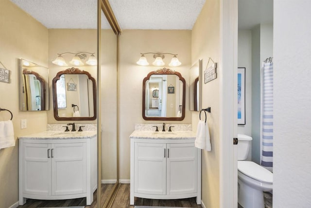 bathroom featuring a textured ceiling, toilet, and vanity