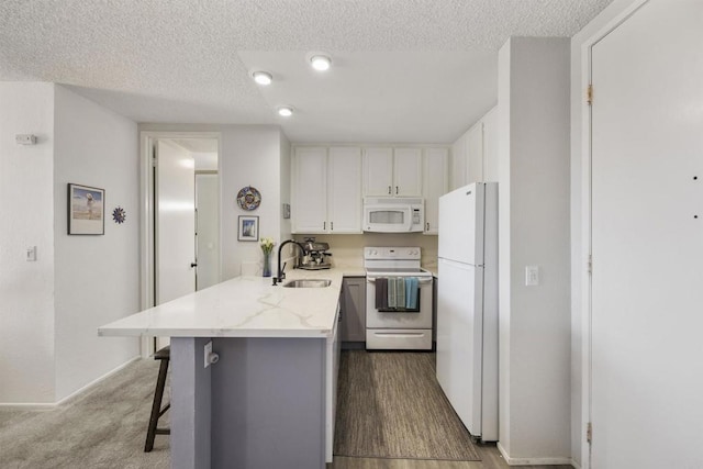 kitchen with white appliances, white cabinets, sink, kitchen peninsula, and a breakfast bar