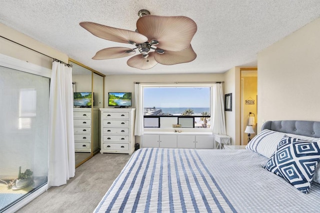 bedroom with light carpet, ceiling fan, and a textured ceiling