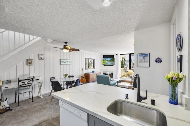 kitchen with ceiling fan, white dishwasher, a textured ceiling, light stone counters, and sink