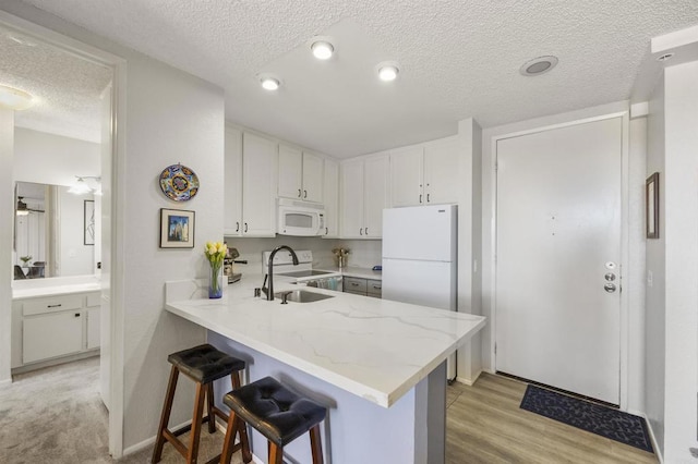 kitchen featuring white appliances, white cabinets, and kitchen peninsula