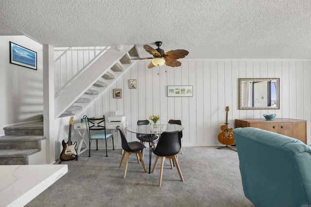 dining room with carpet, ceiling fan, and wood walls