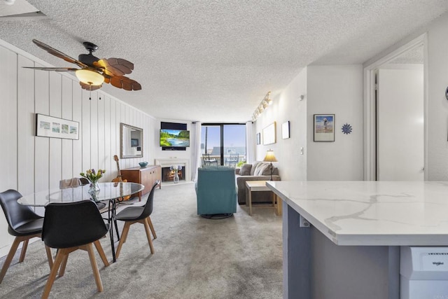 dining room featuring a textured ceiling, ceiling fan, a wall of windows, and wood walls