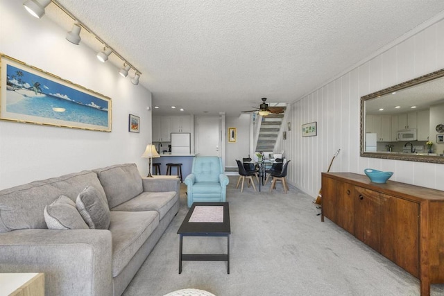 carpeted living room featuring ceiling fan, rail lighting, and a textured ceiling