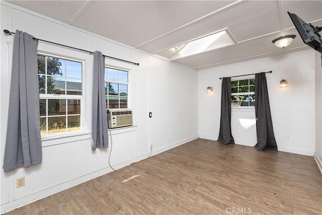 empty room featuring a skylight, cooling unit, and hardwood / wood-style flooring