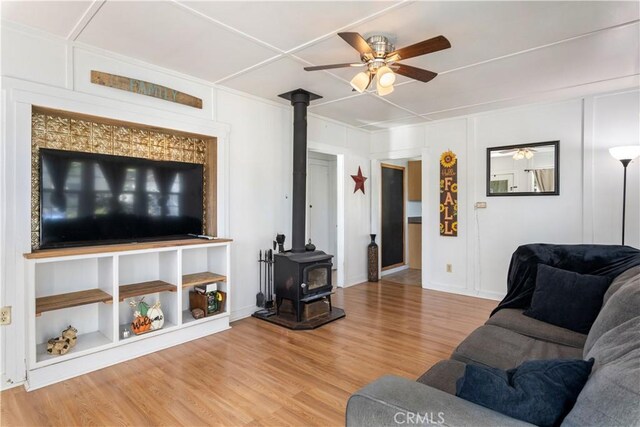 living room featuring ceiling fan, a wood stove, and hardwood / wood-style floors